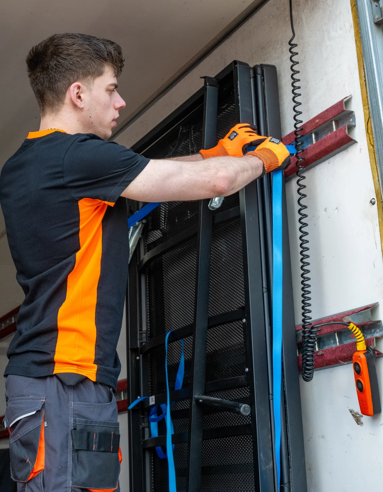 Monteur met oranje handschoenen verplaatst serverrek tijdens spoedontruiming van een bedrijfspand