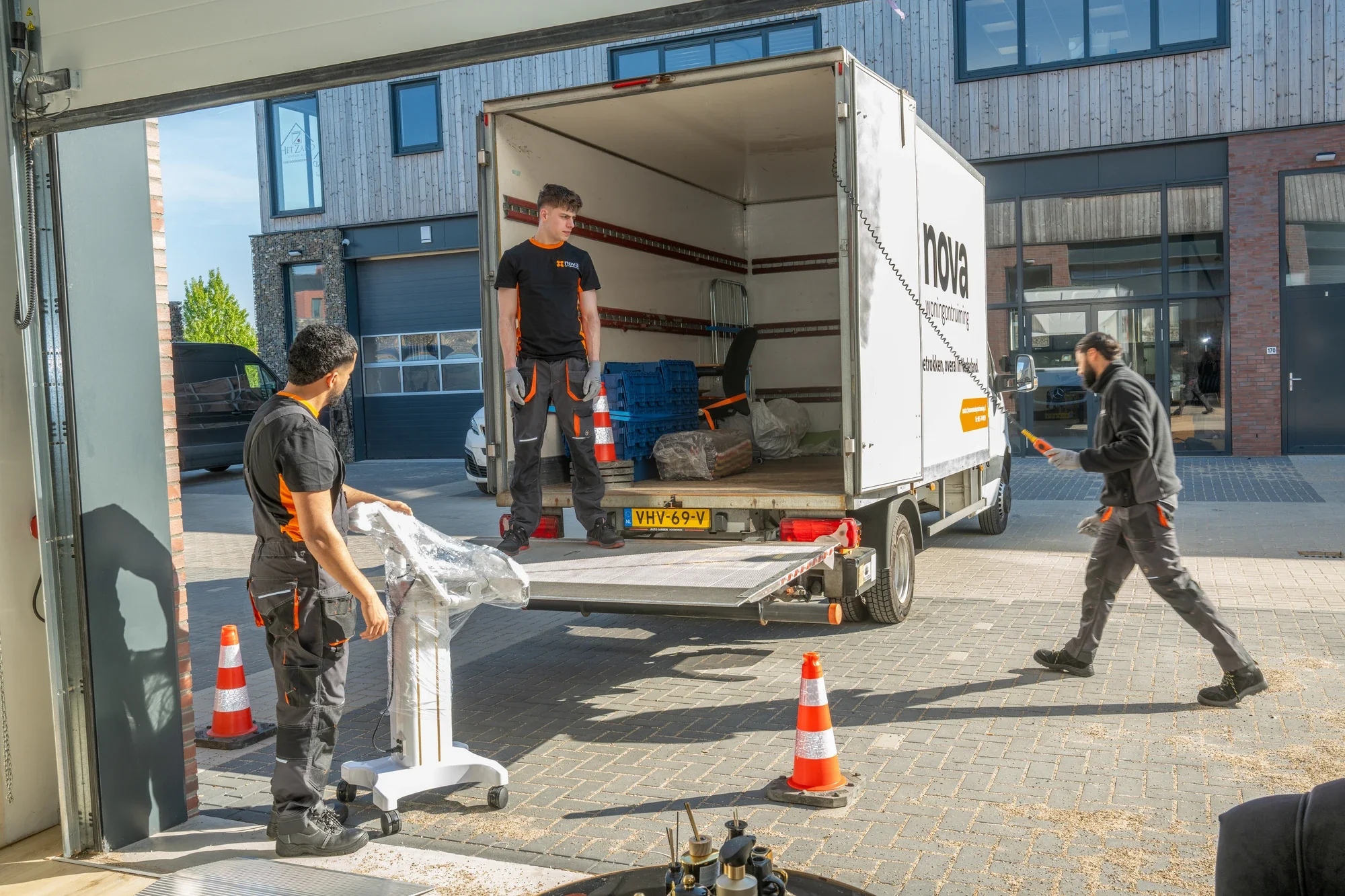 Nova staff members placing a wrapped item of furniture on the tail lift of the box lorry