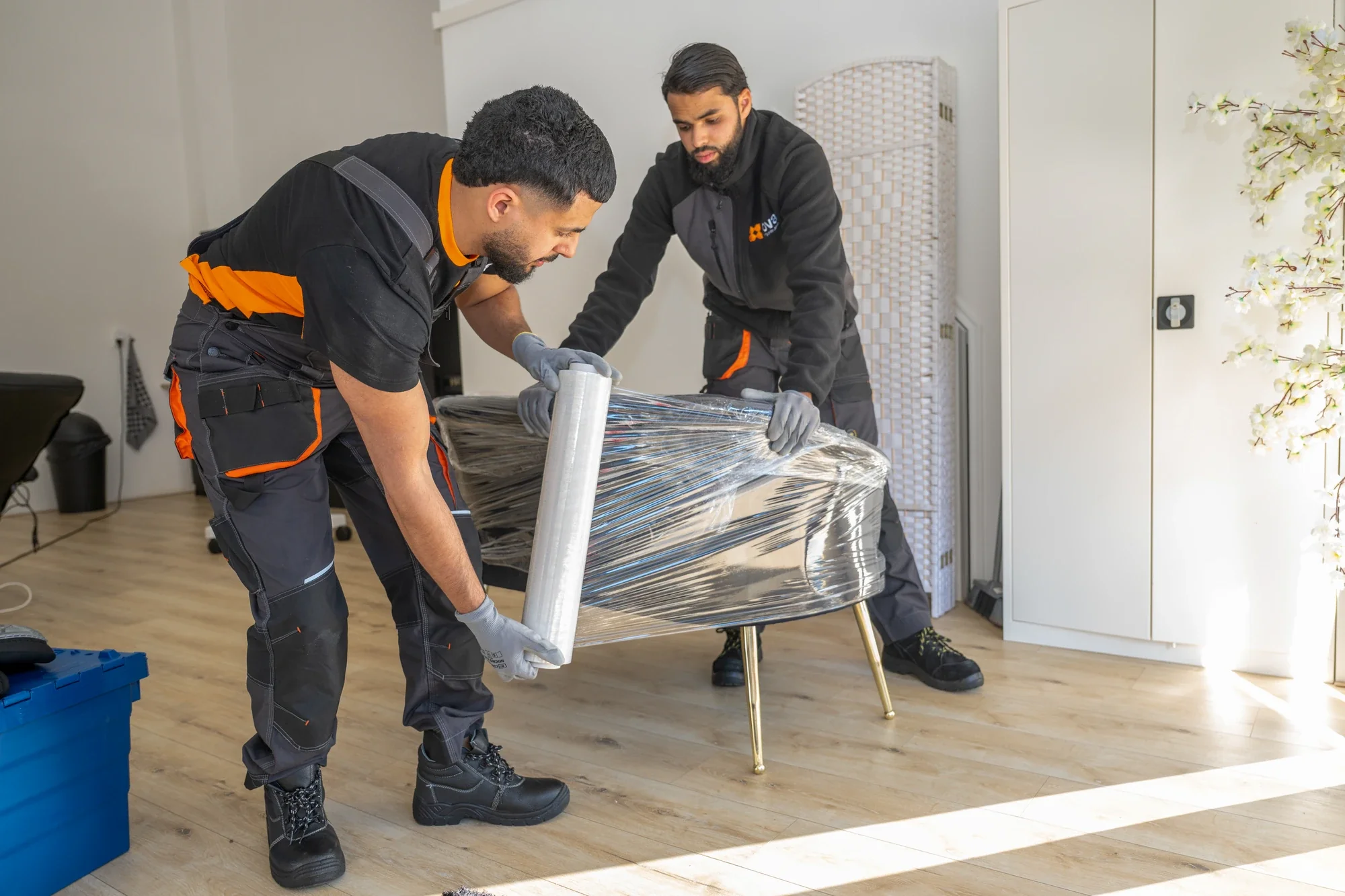 Two Nova employees wrapping an armchair in stretch film together