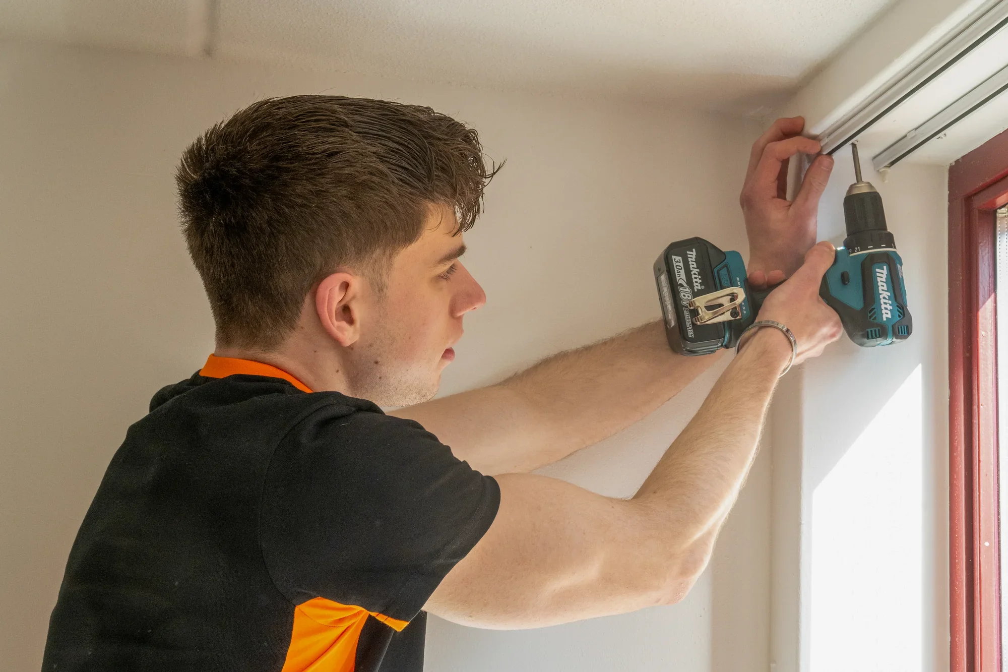A Nova employee unscrewing a curtain rail with a cordless drill