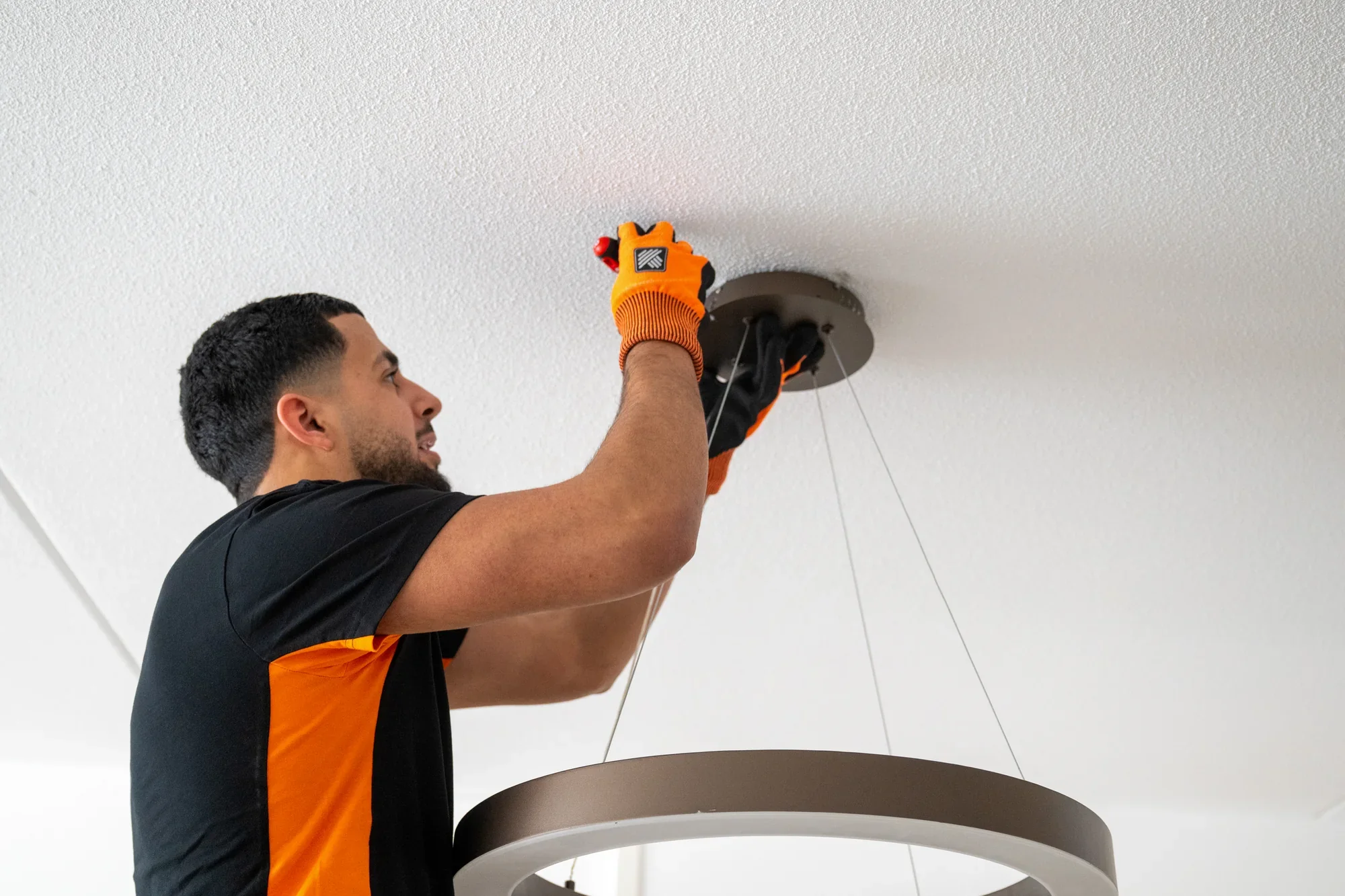 A Nova staff member unscrewing a round pendant light from the ceiling