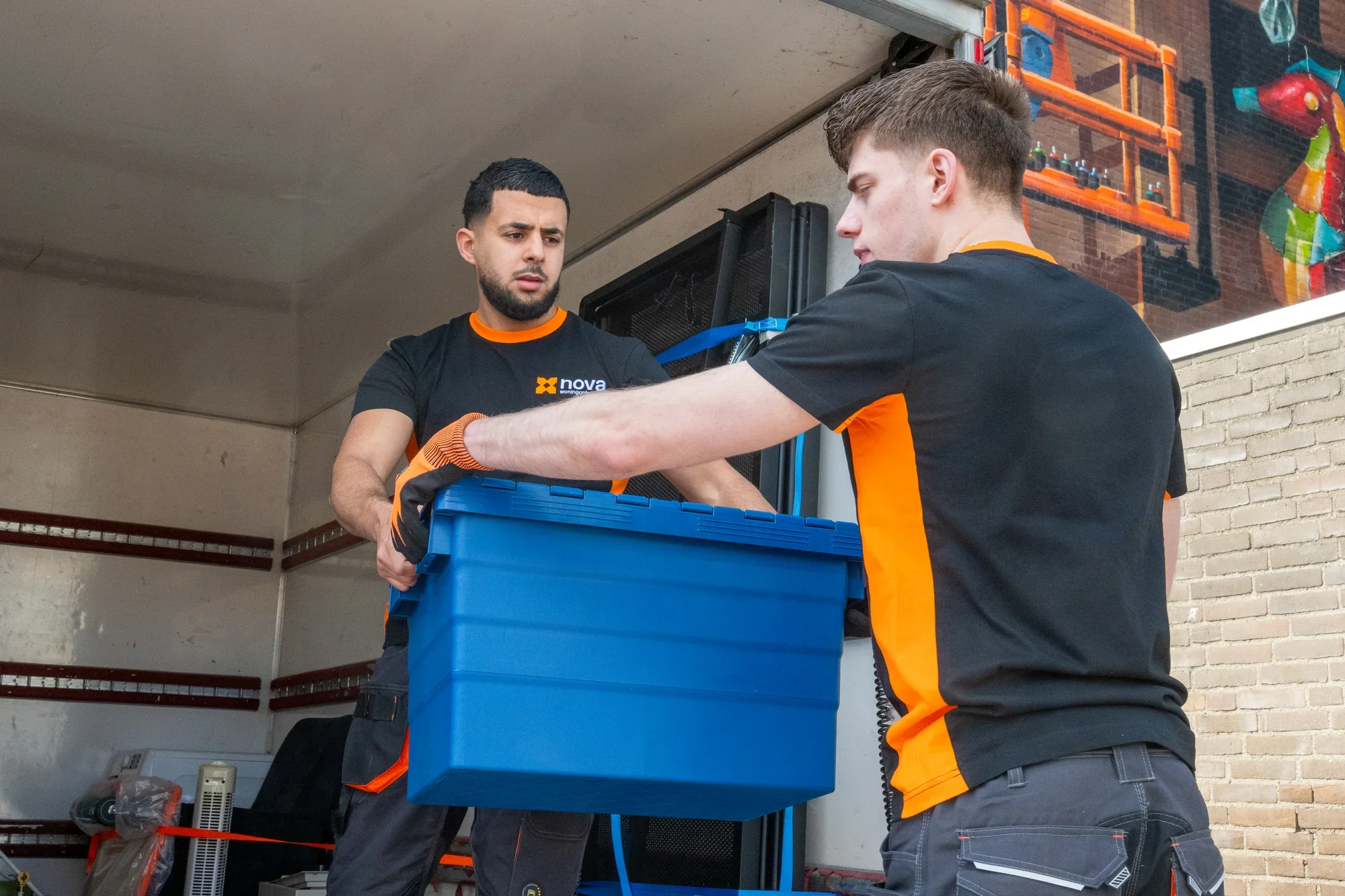 A Nova employee passing a blue plastic crate into the load bed