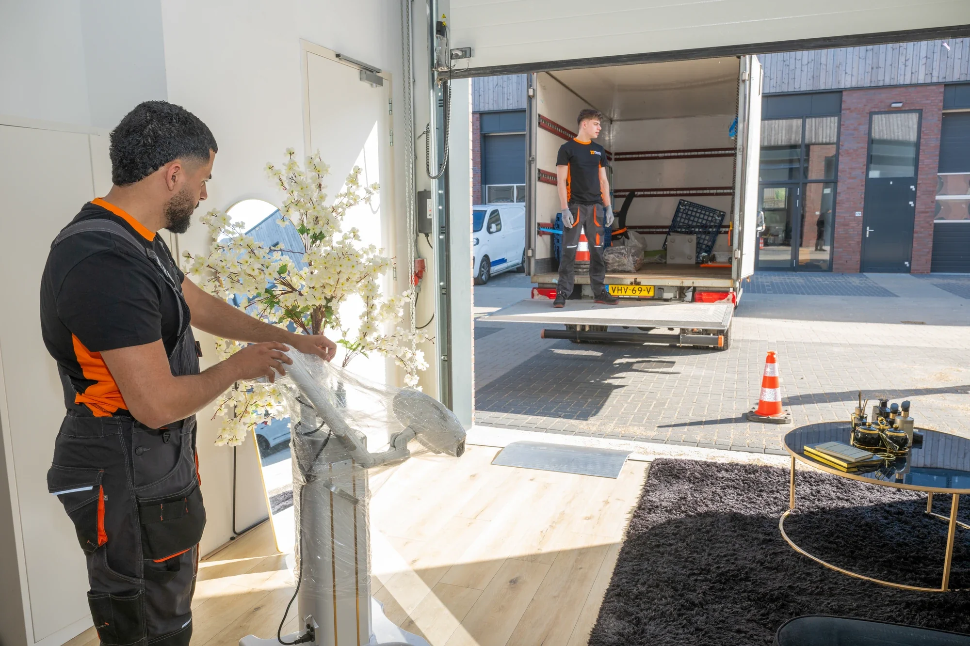Nova staff member wrapping film around a fragile object, with the open box truck in the background
