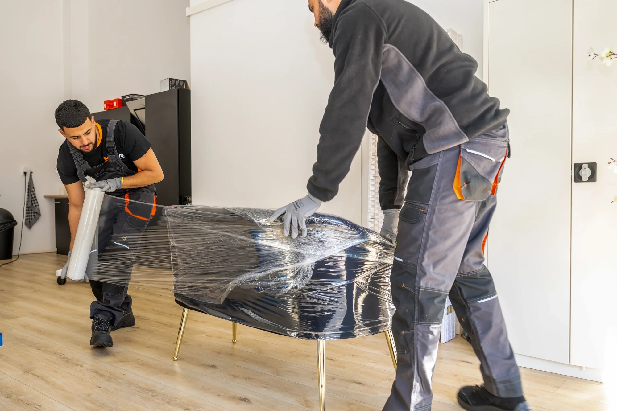 Two Nova staff wrapping a table in clear film