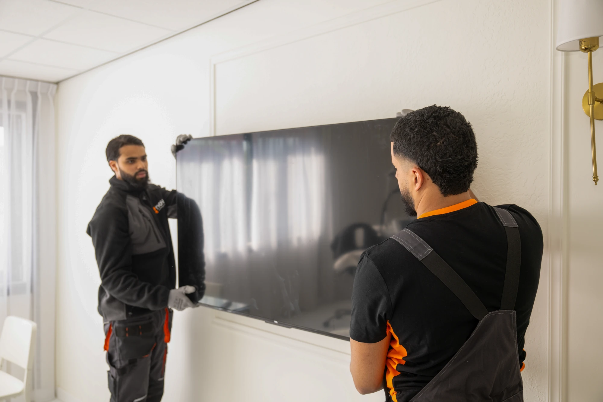 Nova staff member taking a television off its wall bracket while a colleague holds the screen