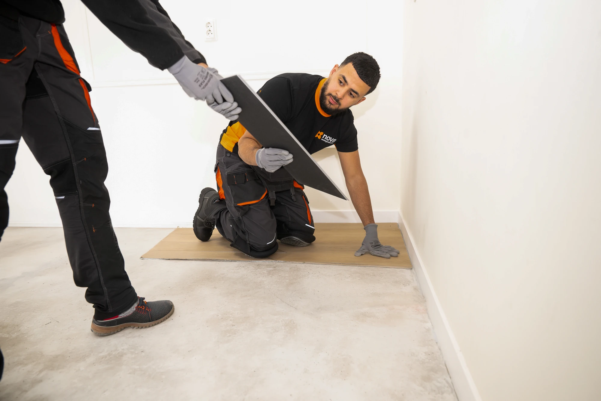 Two Nova staff members lifting the floorboards out of an empty room