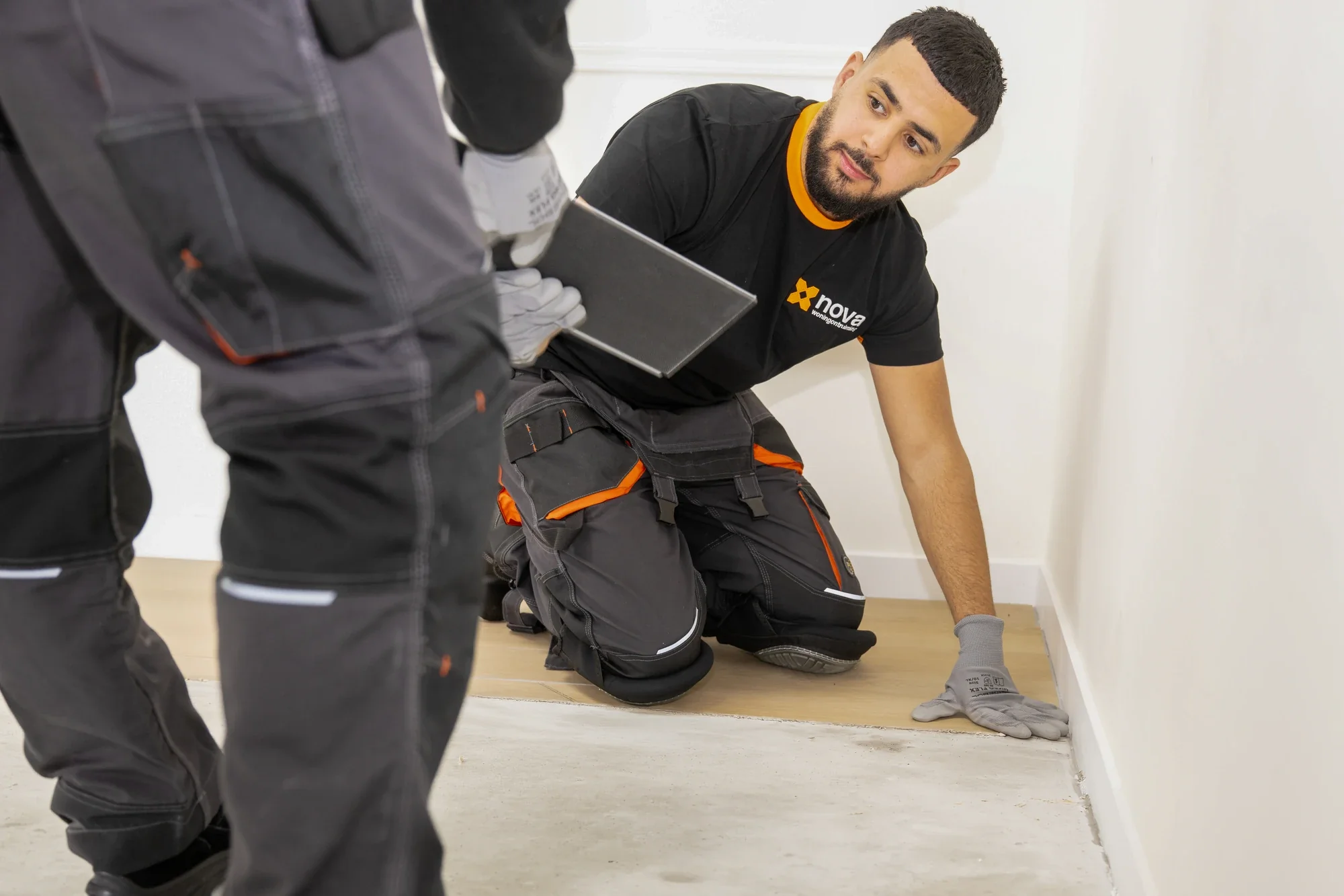 Nova employee prising up a floorboard along the skirting with a scraper