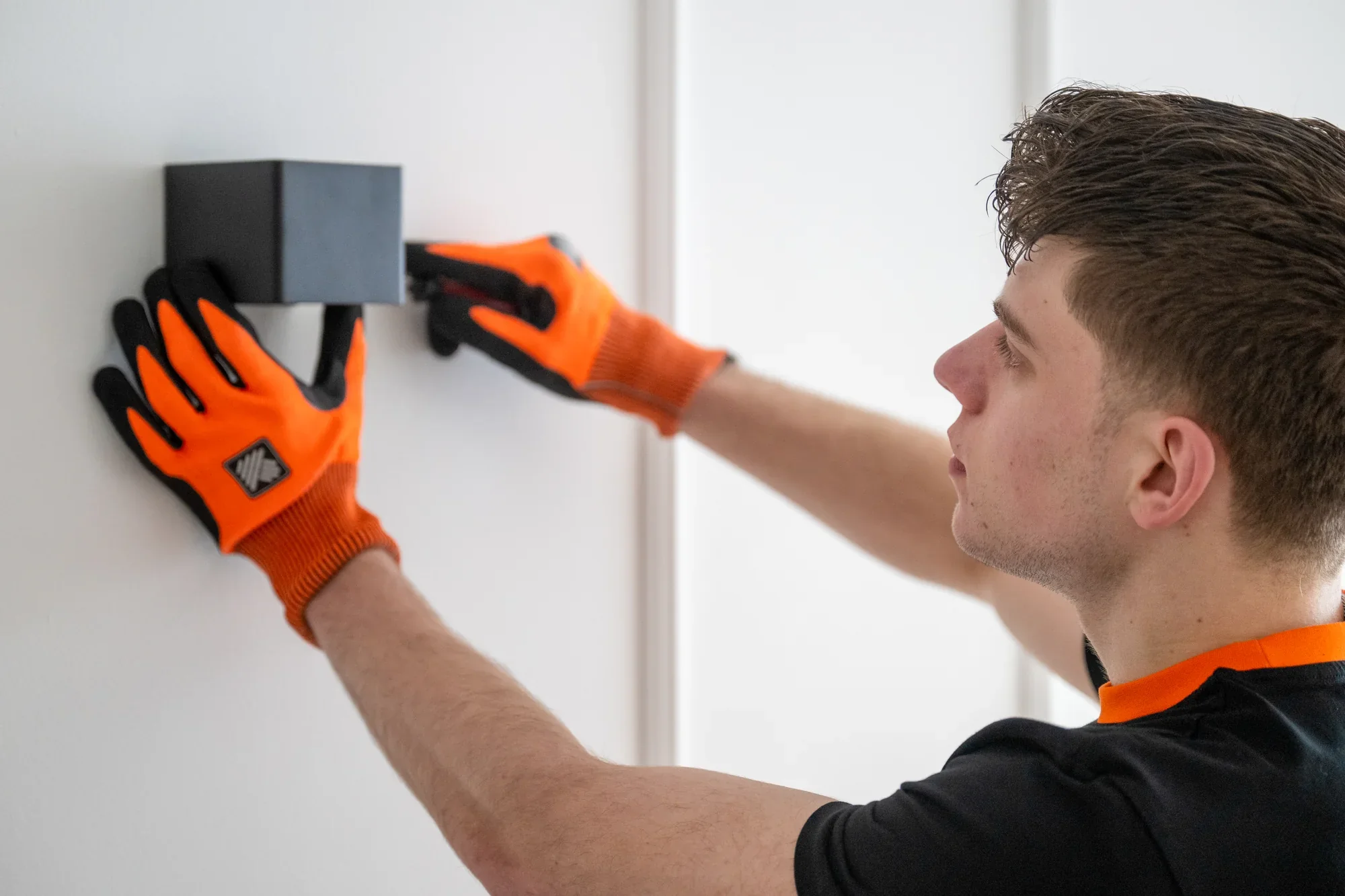 Nova employee loosening a wall bracket from a white wall with a screwdriver